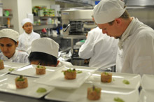 Students in Chef Whites cooking at the commercial cookers in the VenU Training Kitchen