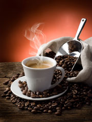 Steaming cup of Espresso coffee sitting on loose coffee beans