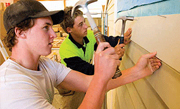 Students nailing weatherboards onto a house