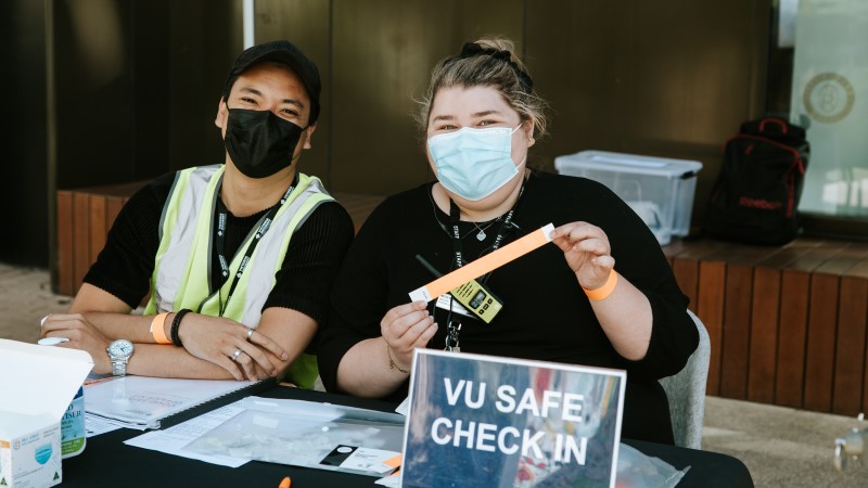   Two COVID Safe Officers seated at a VU Safe check-in desk