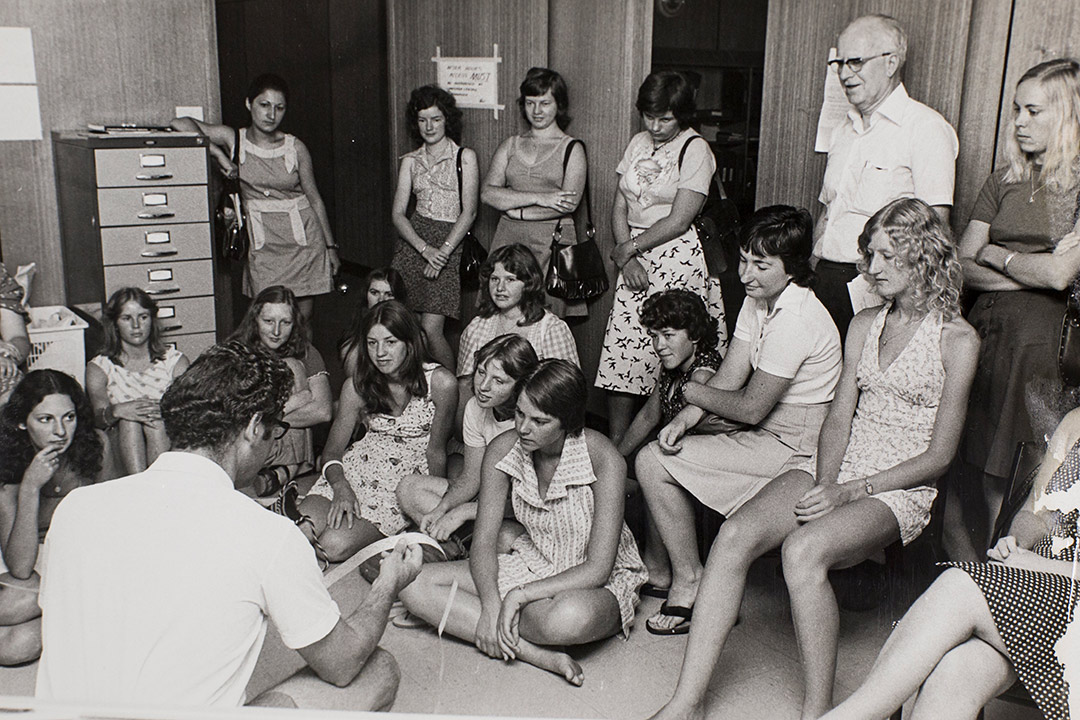 black & white image of young women in 1960s style clothing, sitting casually in a class room