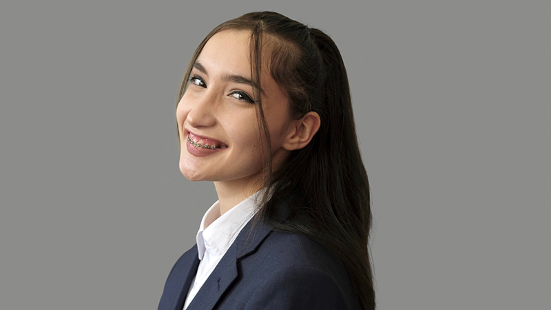 Young female student in a professional shirt and blazer smiles at the camera