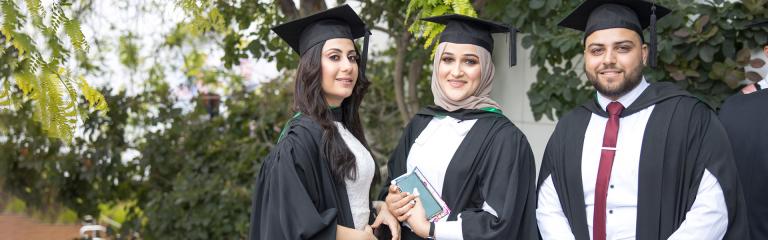 Victoria University students in graduation gowns, smiling proudly at the camera