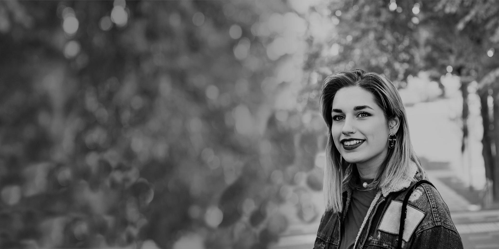  Black and white image of a student standing among trees.