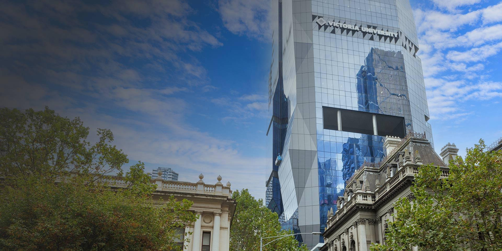 Modern, shiny tower block with Victoria University logo, behind traditional buildings
