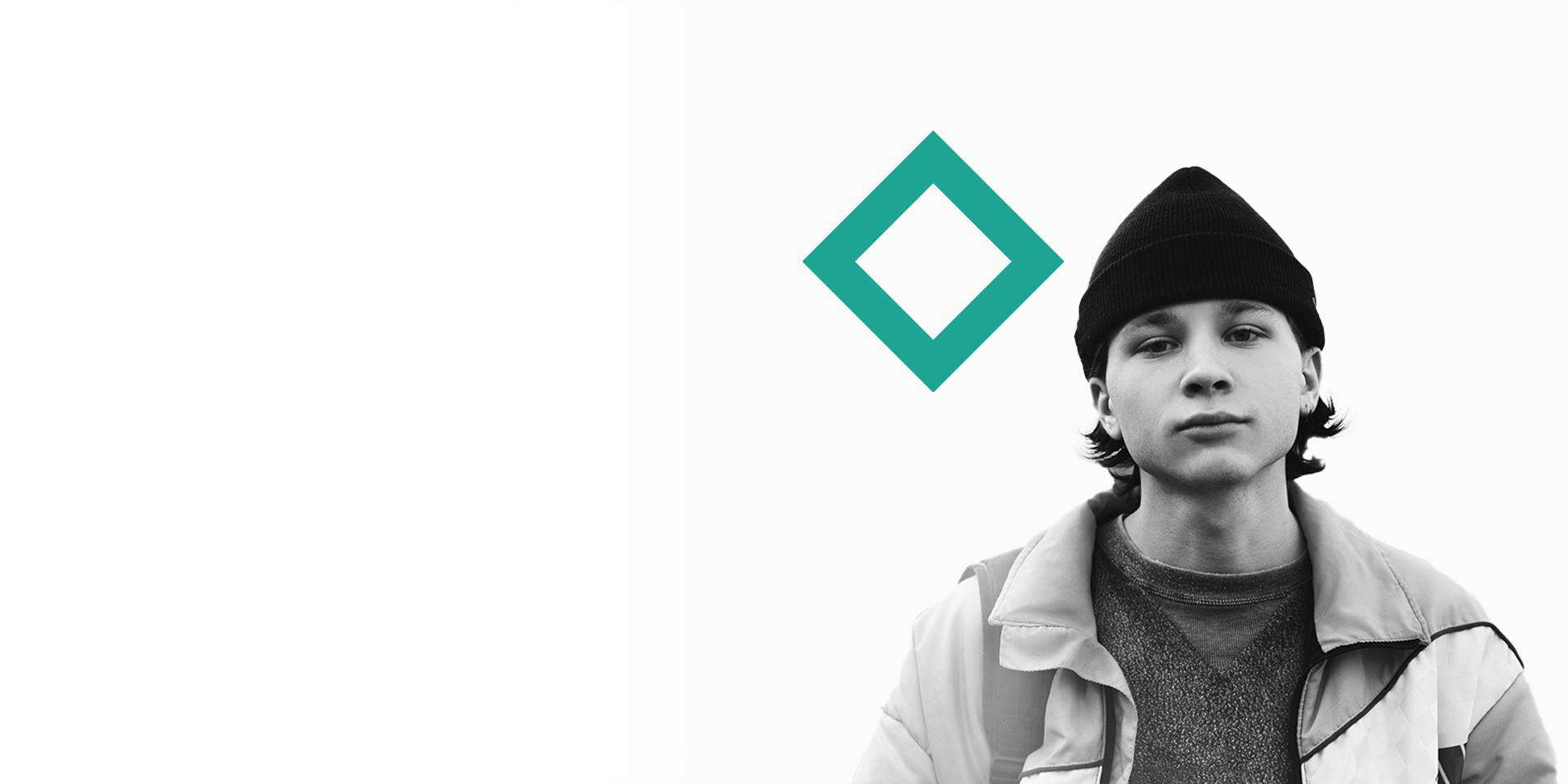   A young man in casual clothes poses in front of a stylised teal diamond logo