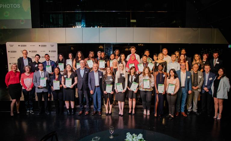 A large indoor photo of a diverse group of approx 20 award winners