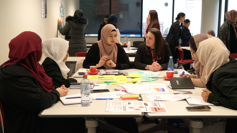  Program participants sitting around a table discussing their group project. 