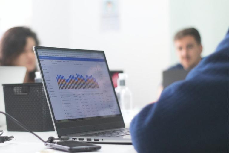 Three people sitting around a computer with data and graphs on the screen