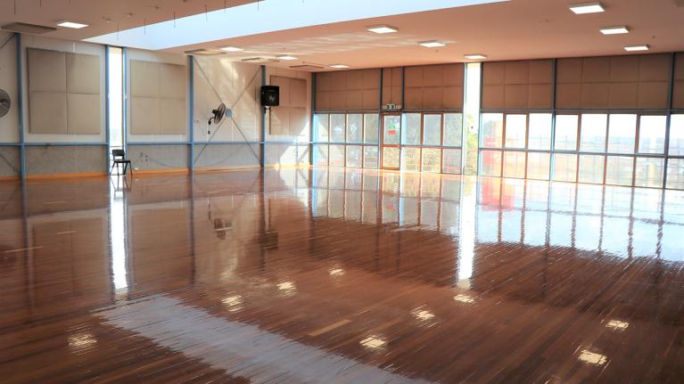A bright, modern, large dance studio with wooden floors and big windows