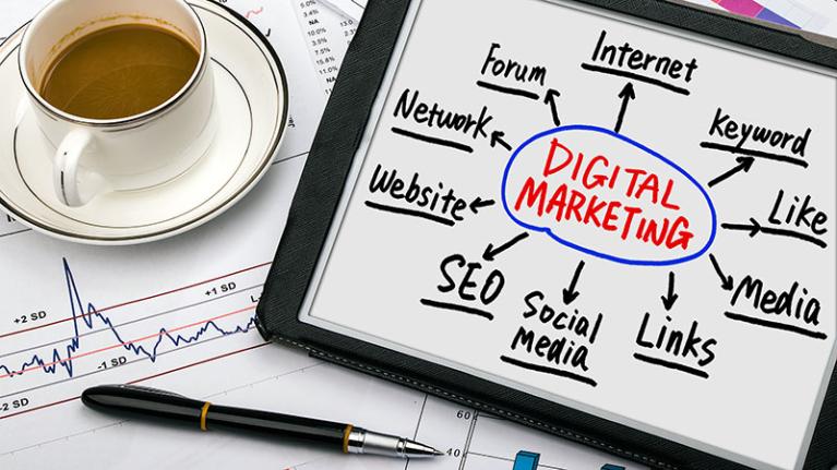 Coffee cup and tablet with Digital Marketing information written upon it.
