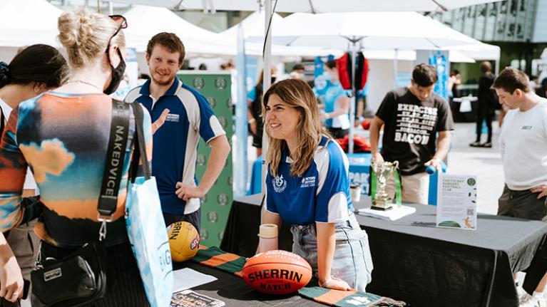  Student talking to VU sport students with a Sherrin football at Footscray Park O-Fest