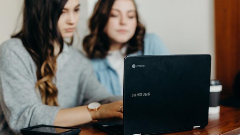  two teenage girls looking at laptop