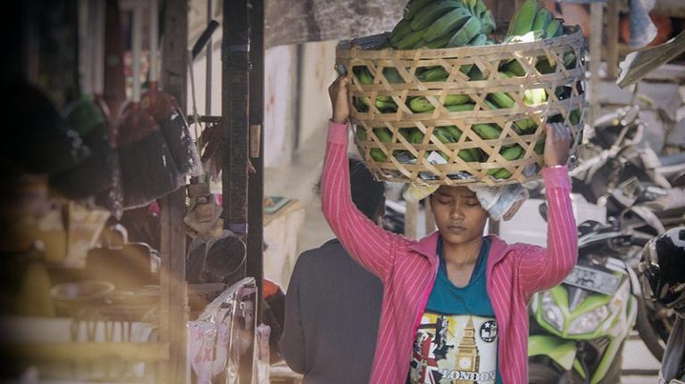 Woman carrying a basket on her head through a market