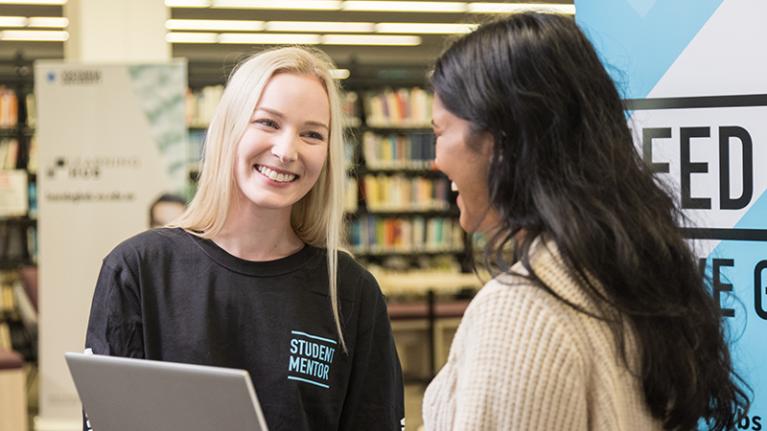 A student mentor smiles welcomingly at a student