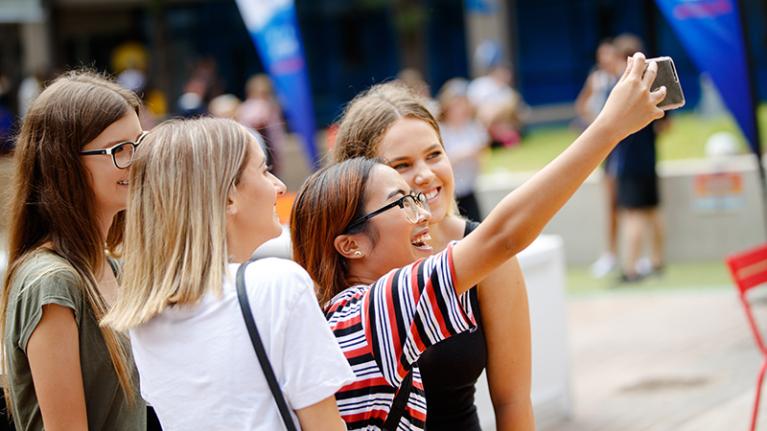  4 students at a VU event posing for a selfie on a phone