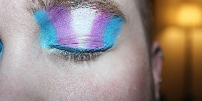 It is important not to judge another by their gender identity or deny that it exists. People with the colours of the transgender flag on their eyelid.