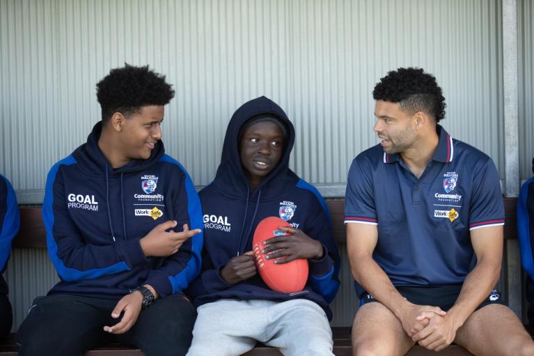 three Western Bulldog players sitting together, in the players section of an oval