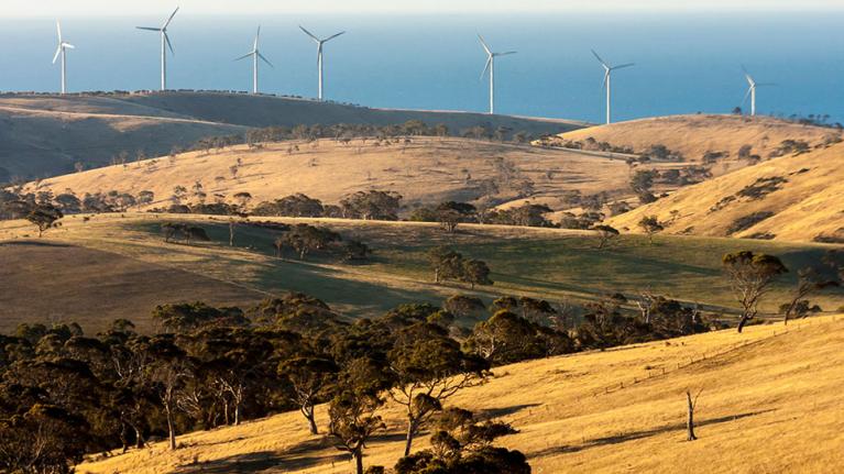  Wind turbines on a hill in front of the ocean in Australia.