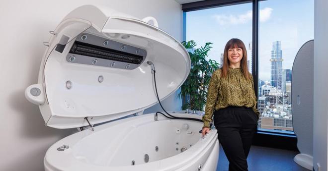 Well presented woman, standing by a space-age looking space treatment with the cityscape in the background