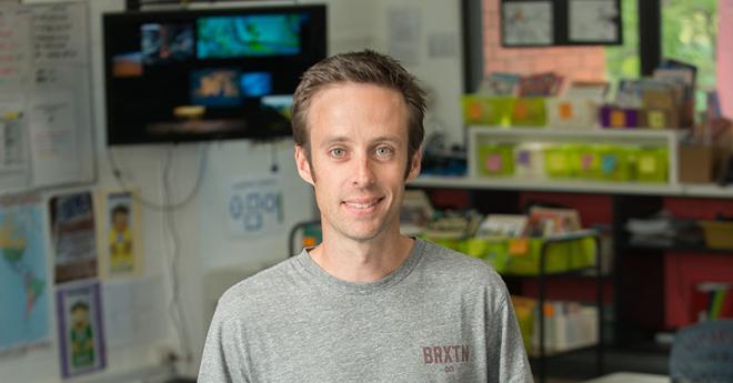 Ben Foster, past Bachelor of Education (P-12) student standing in a primary school classroom.