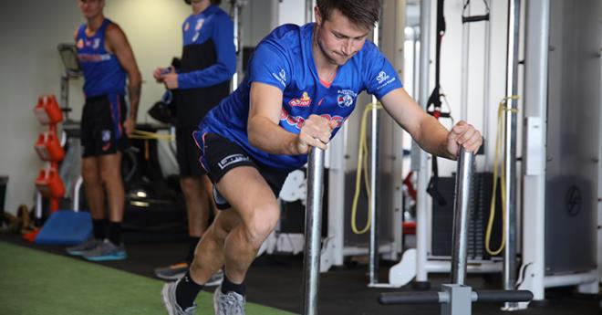 a young man in red and blue sport uniform uses gym with specialised equipment