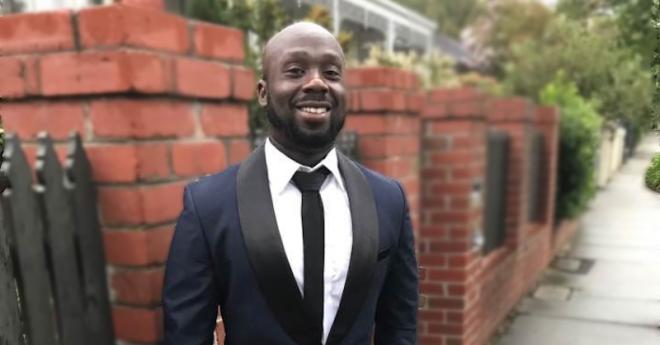 Diploma of counselling student in a suit, outside, smiles at the camera 