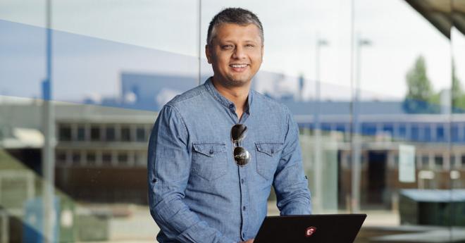 Man with computer, professionally dressed, smiling at camera