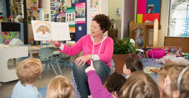  An early childhood teaching student reading to children in the classroom.