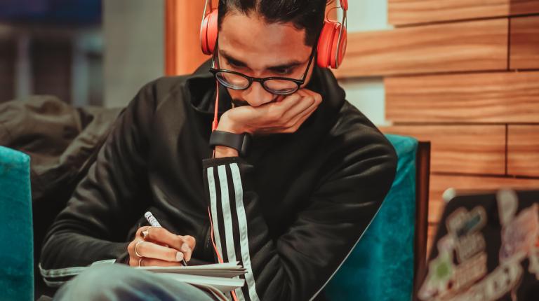  Man listening to headphones and taking notes