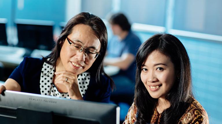   	Teacher in Bachelor of Information Technology teaching student on computer. 