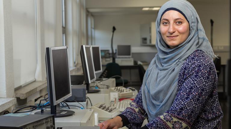  female student posing at computer in a computer lab