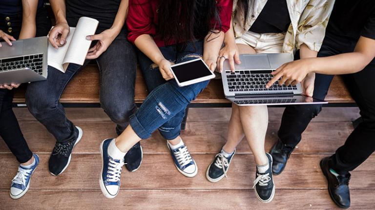  A group of students sitting together holding laptops and tablets. 