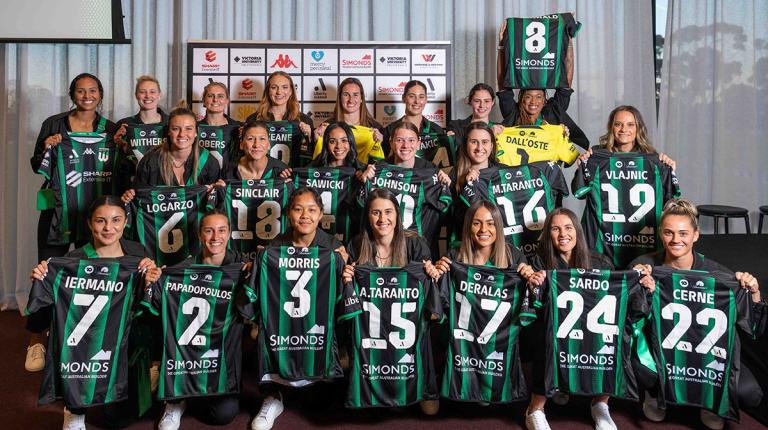 Women's football team proudly hold up team jerseys