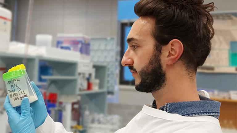 Davor Daniloski's work may lead to resolving a long argument in the dairy industry. A young male scientist in a white lab coat examines 2 sample containers