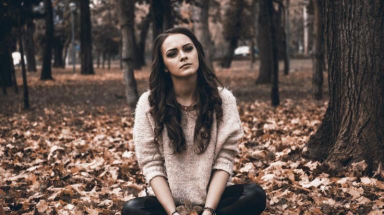 Girl sitting on ground in leaves
