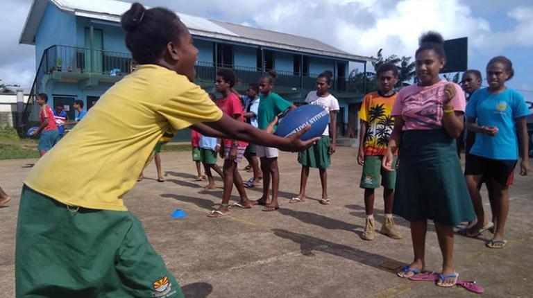 Girls and women in Vanuatu are learning the skills of AFL. A Guide created by VU students and soon to be released will help them enjoy the benefits of the game. girls passing the footy in Vanuatu