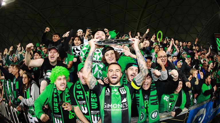 VU student Josh Risdon holds the A-League trophy and celebrates with fans after Western FC win the 2021/2022 Grand Final.