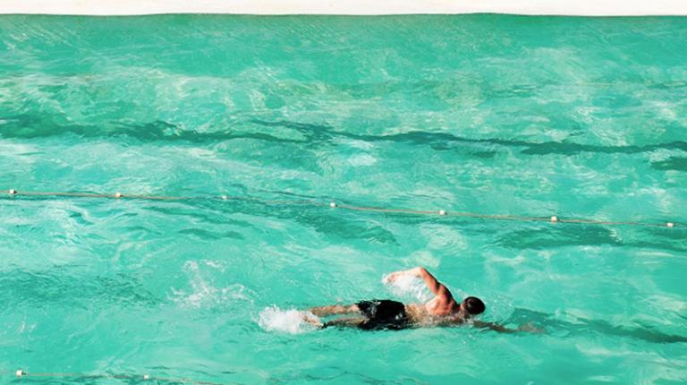 Man swims in a pool near the ocean