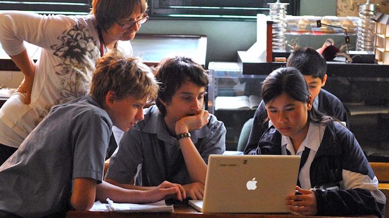 School students and teacher looking at a computer screen