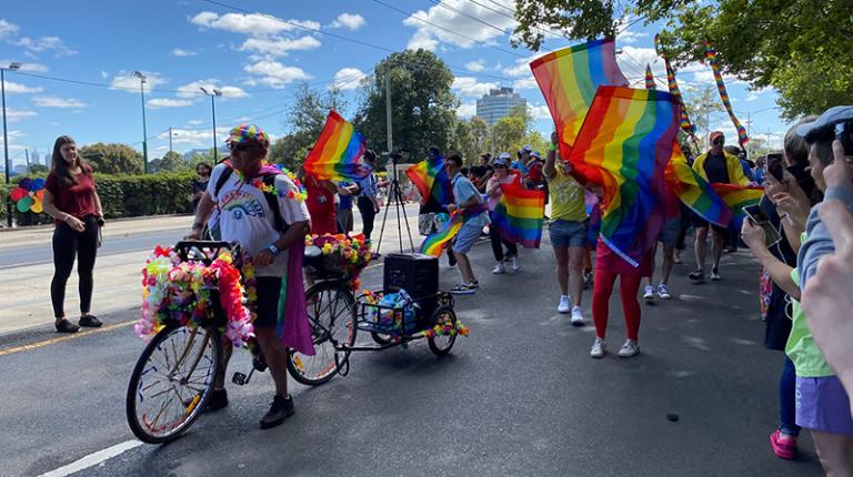 A group on bikes and on foot waving rainbow flags