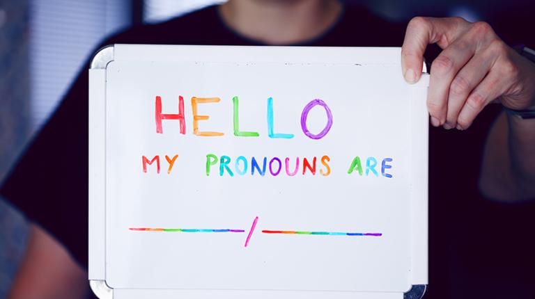Person holding sign that reads 'Hello, my pronouns are...' (photo by Sharon McCutcheon on Unsplash)