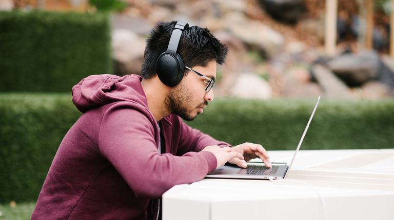 Student using a laptop outdoors on campus 