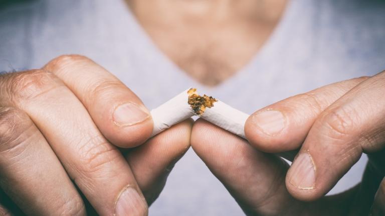 man breaking a cigarette in two.
