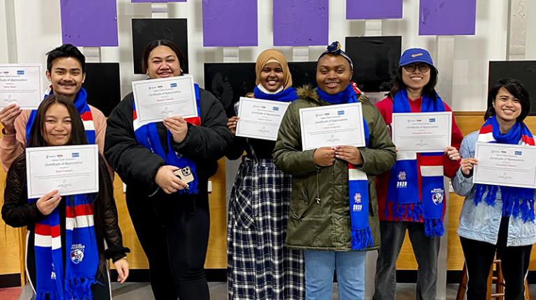 Melton Health Champion participants holding certificates after completing the program. Image courtesy of Simon Rodder and the Western Bulldogs Community Foundation. 6 students of various cultural backgrounds hold certificates, smiling