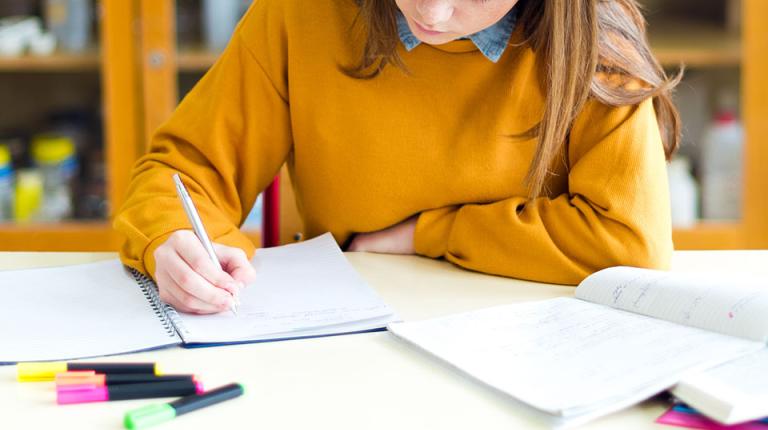  A year 7 student student in a yellow jumper does homework.
