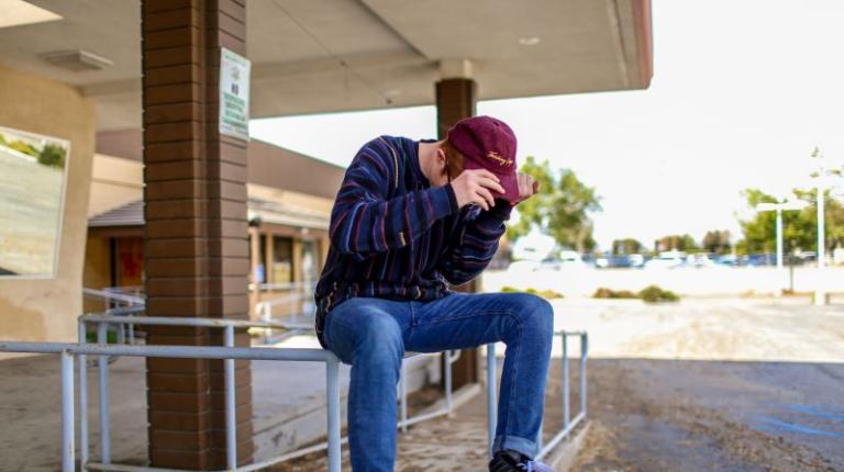 Young person sitting on rail next to building