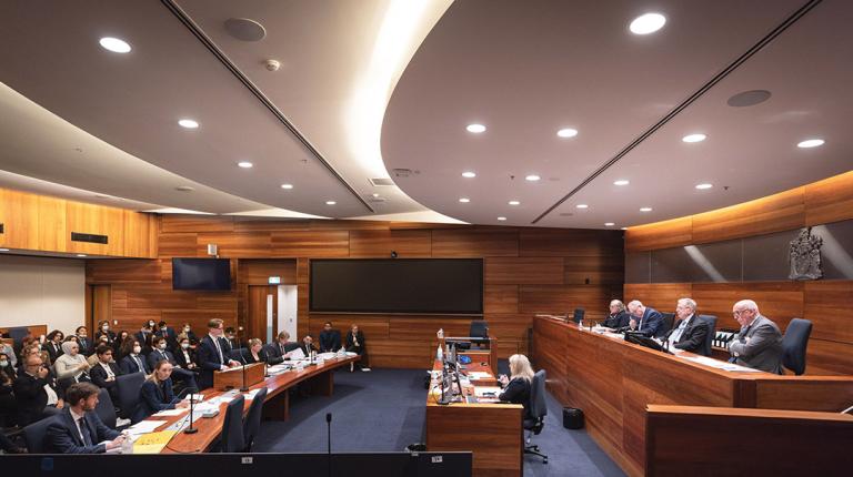 a court room with a panel of judges and audience of young people in suits