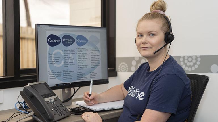  Lifeline volunteer sits in front of a phone and computer.