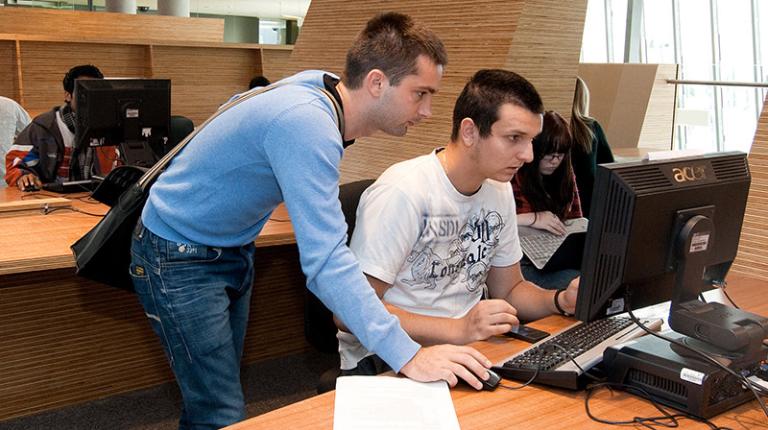  IT and cyber students collaborate at a computer.